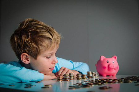 孩子数钱,男孩把硬币放进储蓄罐照片