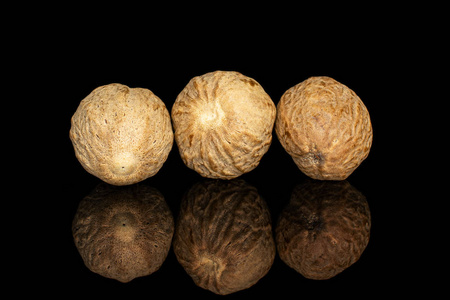 地面上的圆光黑色玻璃上分离的干棕色肉豆蔻照片