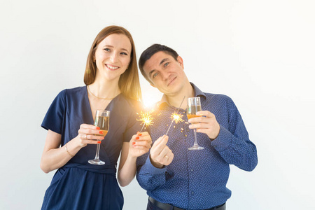 男人和女人在白色背景上用孟加拉灯和香槟酒杯庆祝圣诞或新年夜的聚会。