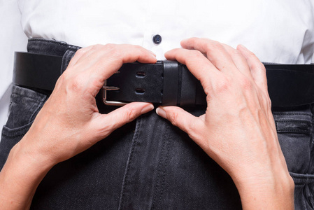 女人用手解开男人牛仔裤上的皮带照片