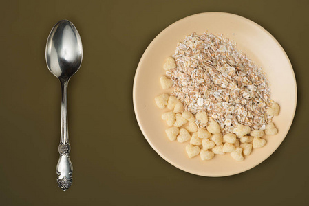 米色盘子上的麦片粥配棕绿色背景.muesli在板顶视图上。健康饮食。健康早餐。