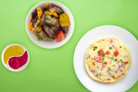 煎蛋卷，白盘子，彩色背景。健康早餐俯视图。乡村食品
