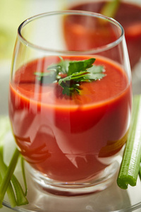番茄汁放在白色盘子里，配以芹菜和欧芹。健康饮食理念