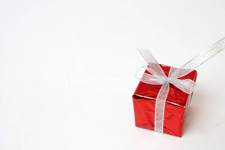 Beautiful red gift box with a silver bow on a white background. 