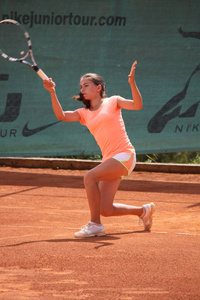 漂亮的年轻女孩在开放的网球场上打网球