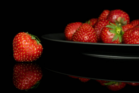新鲜红草莓隔离在黑色玻璃上