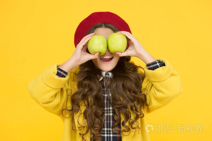 吃苹果有助于学习.小孩拿着黄色背景的苹果.