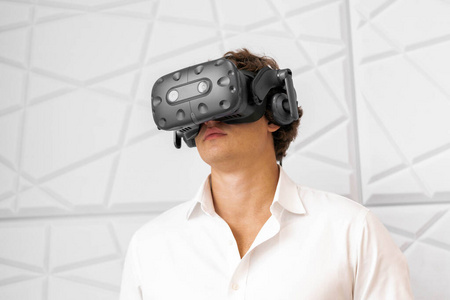 年轻兴奋的男子戴着虚拟现实护目镜在现代明亮的合作办公室。虚拟现实体验。