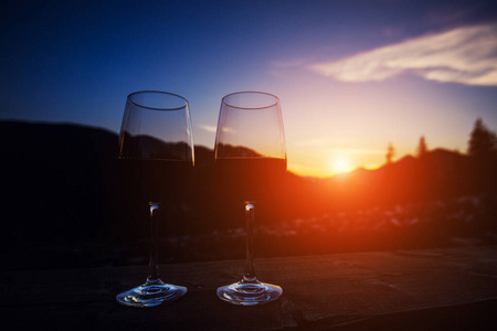 两杯葡萄酒在夕阳下戏剧性的天空山景