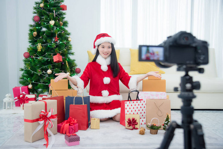 Young beautiful asian girl in santa claus dress recording video 