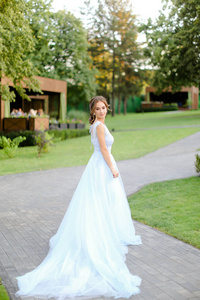 白人新娘站在花园里，穿着白色长裙。