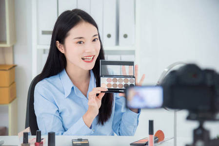 Beautiful asian girl holding eyeshadow palette talking about her