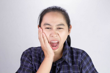 亚洲妇女用手触摸脸颊，因为她牙痛。牙科保健和健康概念。