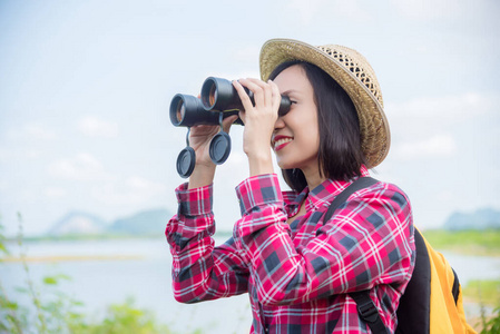 Beautiful Asian woman using binoculars to see the birds 