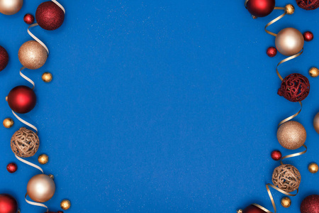 新年和圣诞作文。红色和金色闪亮的球，蓝色纸背景上的装饰丝带