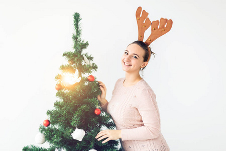 假日概念有趣的年轻女子装饰在白色背景上的圣诞树。等待圣诞节。