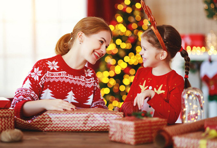 happy family mother and child pack Christmas gifts at home near 