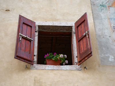 黄色墙上有花的小窗户。意大利