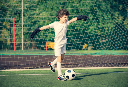 儿童夏季足球锦标赛。足球俱乐部。游戏的情感和快乐。年轻的守门员。儿童足球冠军。球场上穿着足球运动服的男孩守门员。运动理念。
