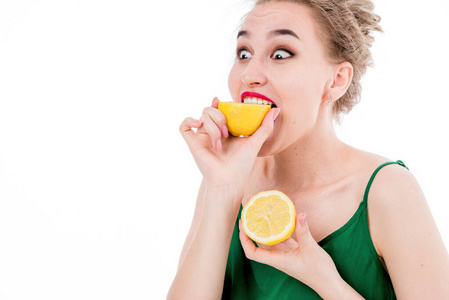 美丽的女孩吃着柠檬，背景是白色的。健康饮食理念