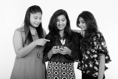 摄影棚拍摄了三个快乐的年轻波斯女性朋友微笑着一起使用一部手机