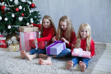三个小女孩在圣诞树新年冬天打开礼物