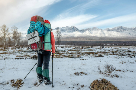 背着一个大背包的女徒步旅行者背着雪山站着。实现目标的途径
