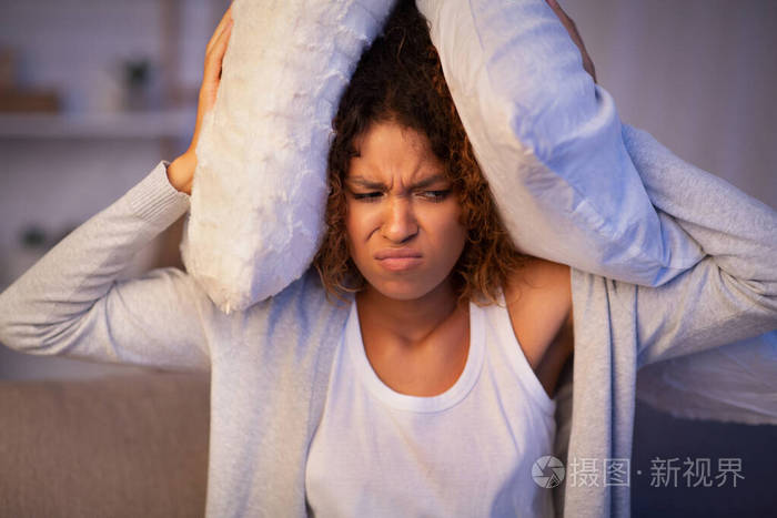 因噪音而被激怒的女孩用枕头捂住耳朵