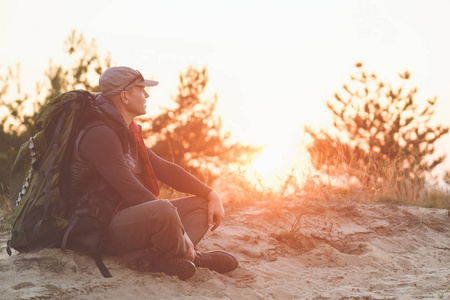 老人背包背着背包的老人坐在夕阳下照片