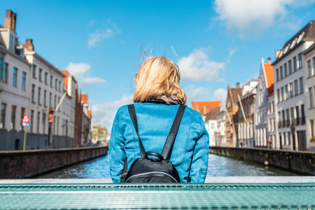 比利时布鲁日市中心，女游客坐着欣赏运河风景