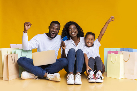 快乐的黑人家庭，有笔记本电脑信用卡和购物袋。