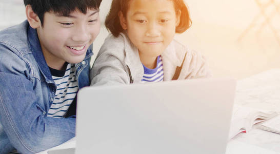 Young asian boy and girl playing with laptop computer at home. 