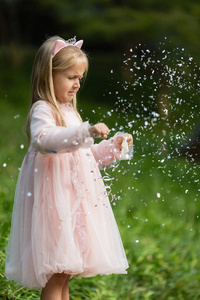 金发时髦的小女孩在公园里扔五彩纸屑。户外生日庆典，趣味儿童休闲