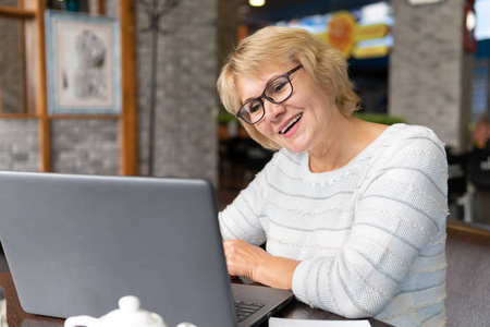 一个女人拿着笔记本电脑在咖啡馆工作，她看社交网络。