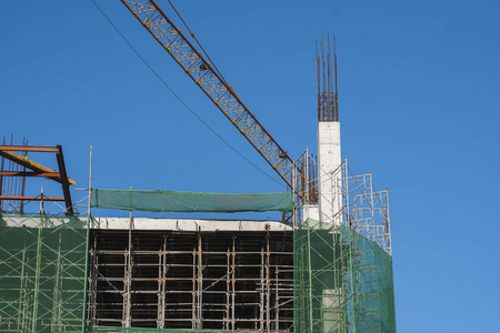 蓝天下的起重机和建筑工地。未完工建筑的金属结构。塔吊用于多仓库建筑。