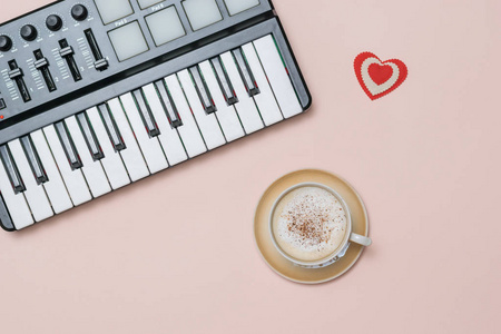 一杯加肉桂的咖啡卡布奇诺和粉红色背景的音乐调音器。