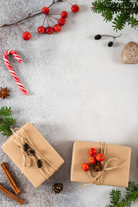 圣诞礼品盒。手工制作的礼物，在灰色混凝土背景上用手工纸冷杉树枝和糖制作。平躺。圣诞节新年促销概念