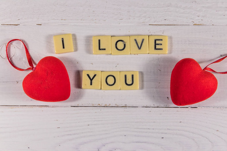 Red hearts and I Love You text on white wooden background