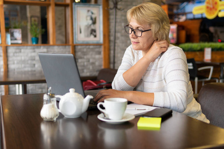 一个女人拿着笔记本电脑在咖啡馆工作，她看社交网络。
