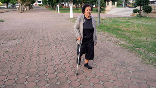 公园里拄着拐杖走路的老年妇女照片