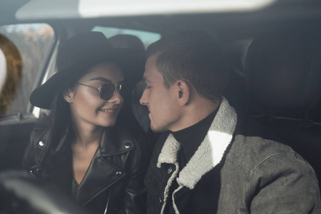 一对快乐的旅行情侣穿着黑色时尚的衣服，坐在车内享受公路旅行，度假概念