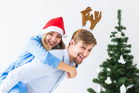 一个滑稽的男人在家里给妻子背着圣诞帽。