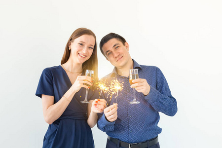 男人和女人在白色背景上用孟加拉灯和香槟酒杯庆祝圣诞或新年夜的聚会。