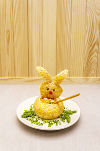 复活节兔子儿童食品概念。温热南瓜奶油汤在新鲜的面包卷，香草和南瓜子在盘中。木石背景。