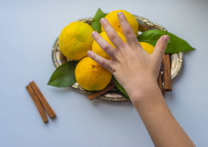 孩子们的手在浅色背景下伸手去摸橘子.那孩子伸手要一片普通话照片