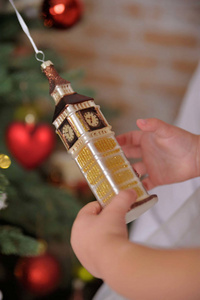 拿着一个枞树玩具的小女孩。圣诞节和新年概念。孩子的手在圣诞树的背景上握着漂亮的圣诞玩具