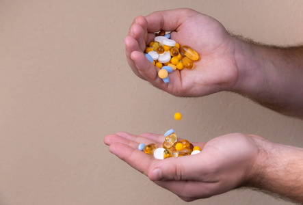 A pile of multicolored pills in a male hand. A man holds pills 