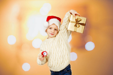 A little boy in a santa hat and in a warm knitted sweater holds 