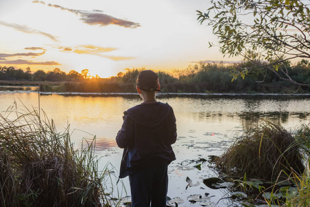 小渔夫黎明时在池塘的岸边捕鱼.照片