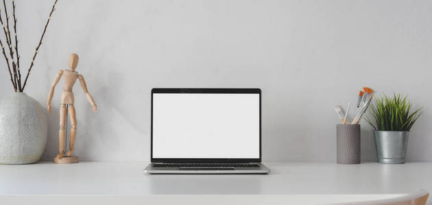 Open blank screen laptop computer in minimal workplace with deco